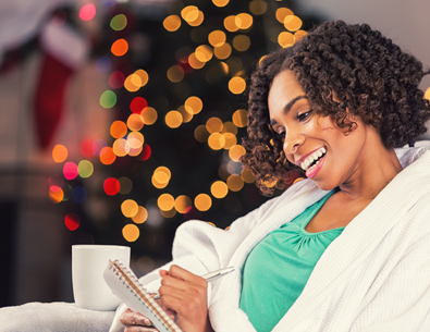 Woman sitting down looking at a book with Christmas tree in background