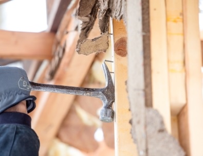 Close up of gloved hand with hammer removing nail from wood