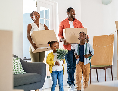 Family with two young children carrying boxes into their new home