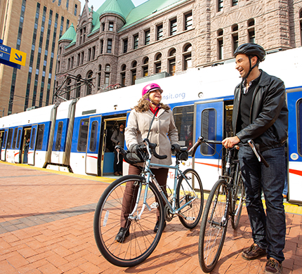 Two people with bikes standing in front of the lighte rail in downtown Minneapolis